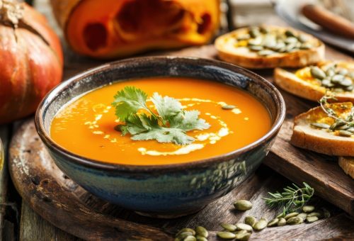 The vibrant pumpkin soup served with toasted bread and fresh herbs.